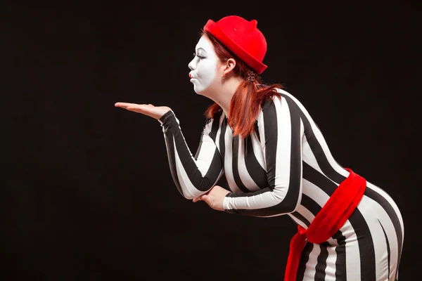 Portrait d'une artiste de mime féminine jouant, isolée sur fond noir. Femme souffle un baiser posant en robe rayée — Photo