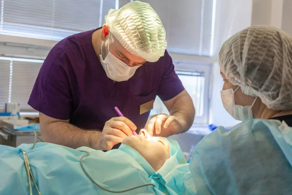 Mężczyzna chirurg robi ślady chirurgiczne na twarzy pacjenta przed operacją blepharoplastyczną — Zdjęcie stockowe