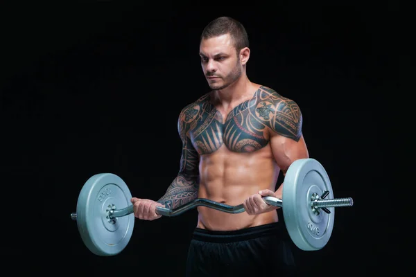 Getatoeëerde sterke gespierde atletische man pompen spieren met lange halter op zwarte achtergrond — Stockfoto