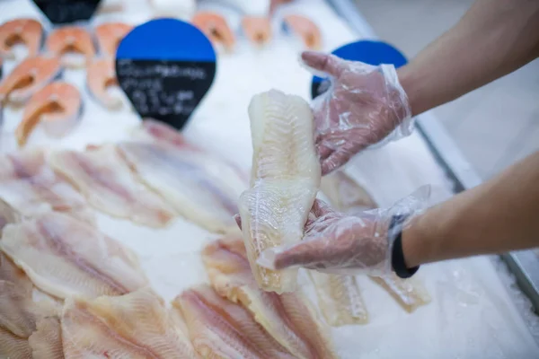 Primer plano de mans manos guantes sosteniendo pescado congelado elegir alimentos en una tienda de comestibles — Foto de Stock