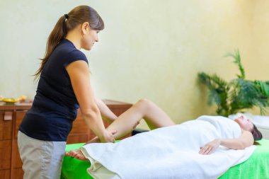 Profesyonel terapist spa 'daki bir kadına Tayland yağı bacağı masajı yapıyor.