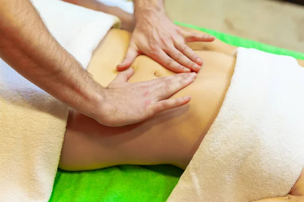 Zijaanzicht van handen masseren vrouwelijke buik. Therapeut oefent druk uit op de buik. Vrouw krijgt massage in spa salon — Stockfoto