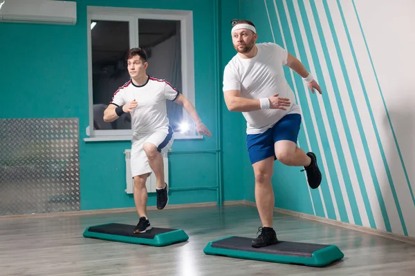 在集体健身课上，胖男人非常刻苦地在台阶上做踏步练习。体重超标 — 图库照片