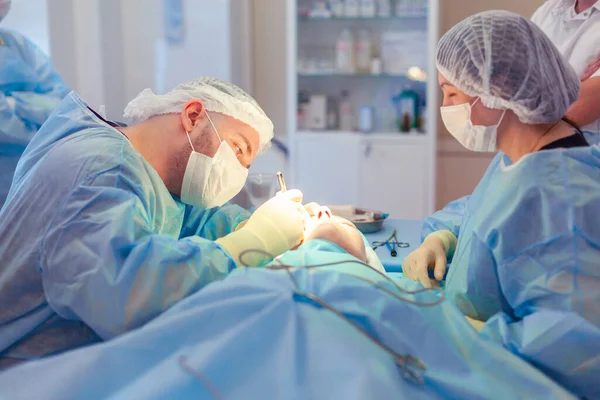 Kirurgen lutade sig mot patienten under operationen. En grupp kirurger arbetar i operationssalen — Stockfoto