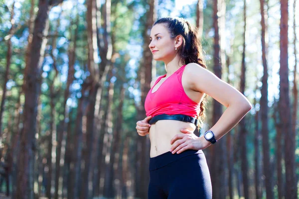 Menina fitness usando monitor de frequência cardíaca para treino na floresta ou rastreamento de sua melhoria da perda de peso — Fotografia de Stock