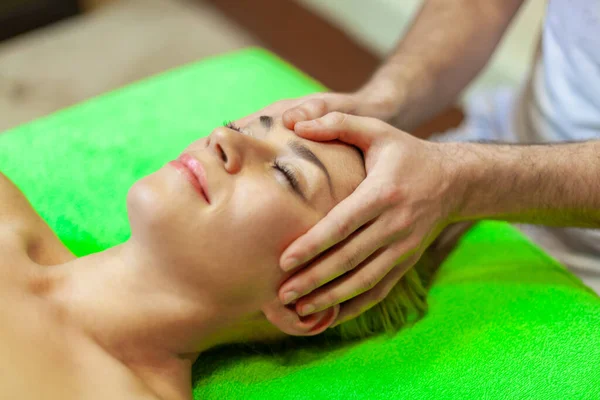 Close up de bela jovem relaxante com massagem facial no spa de beleza — Fotografia de Stock