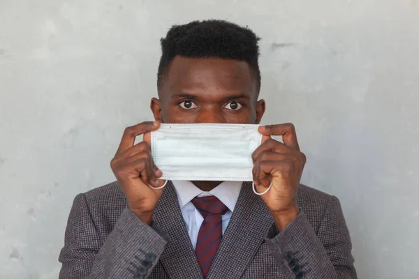 COVID, COVID-19, koronavirüs, salgın. Genç Afrikalı adam koronavirüs enfeksiyonu ve salgını önlemek için koruyucu bir maske takacak. — Stok fotoğraf