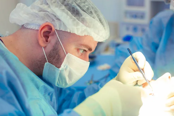 Vista lateral del cirujano masculino que trabaja en el quirófano. Primer plano del médico masculino que realiza la cirugía a un paciente —  Fotos de Stock