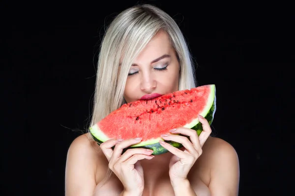Sexy jeune femme blonde pose les yeux fermés voulant mordre une tranche de pastèque isolée sur fond noir — Photo