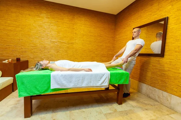 Pleine longueur vue latérale du masseur tire les jambes de la femme faisant massage thaïlandais traditionnel sur le corps de la femme dans le salon de spa. Concept de traitement beauté — Photo