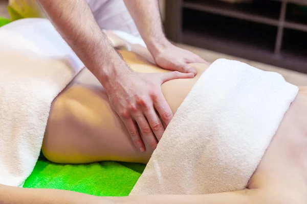 Sidovy av händer massera kvinnlig buk. Terapeut sätter tryck på magen. Kvinna som får massage på spa salong — Stockfoto