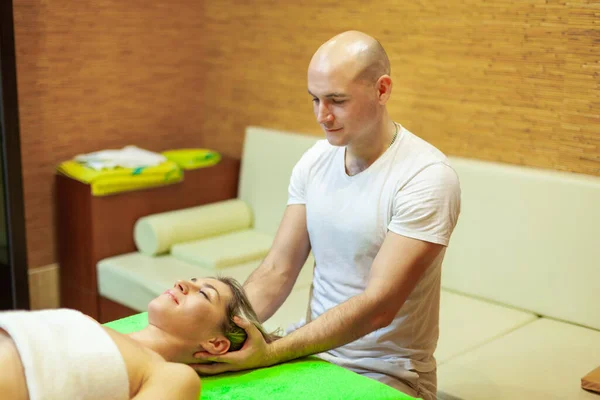Całkowity relaks. Piękna młoda kobieta leżąca na plecach, podczas gdy profesjonalny masażysta masuje jej głowę — Zdjęcie stockowe
