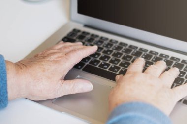 Yakından yaşlı bir kadın dizüstü bilgisayarda klavyede el ele geziyor ve internette bedava ve kopya alanı ile internette geziniyor. Teknoloji, iletişim, bilgi kavramı
