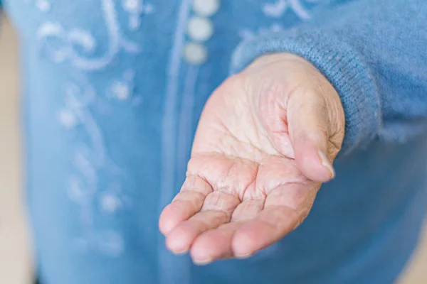 Hand of an elderly woman asks for alms, grandmother pulls a hand