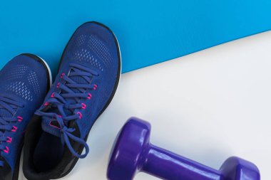 Beyaz arka planda spor aletleri, spor ayakkabıları, paspas ve dambıl. Karşıt aksesuarlar