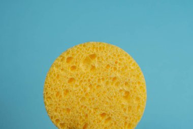 Mavi arka planda yıkanmak için sarı kozmetik sünger