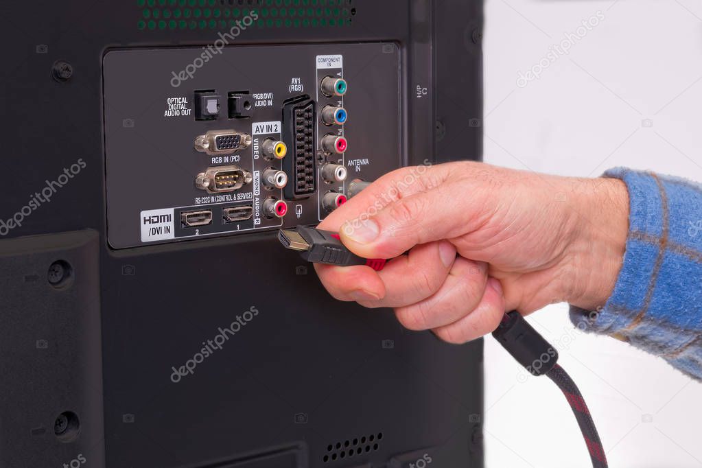 Hand holding HDMI cable in the back of an HDTV box.