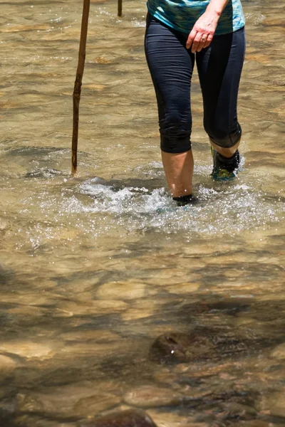 Caminhante feminina andando em um riacho . — Fotografia de Stock