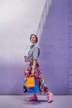 Elinde paketler olan genç ve güzel bir kız. Uzun açık etekli ve açık pembe bluzlu bir kız mağazadan çıkıyor..