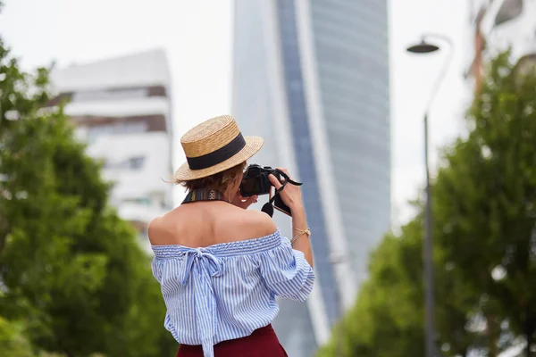 Mujer fotógrafa con sombrero pasea por la ciudad y toma fotos — Foto de Stock