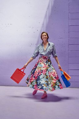 Elinde paketler olan genç ve güzel bir kız. Uzun açık etekli ve açık pembe bluzlu bir kız mağazadan çıkıyor..