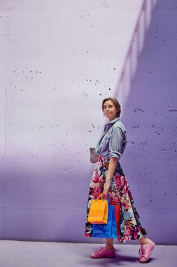 Elinde paketler olan genç ve güzel bir kız. Uzun açık etekli ve açık pembe bluzlu bir kız mağazadan çıkıyor..