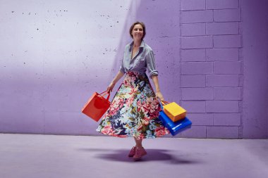 Elinde paketler olan genç ve güzel bir kız. Uzun açık etekli ve açık pembe bluzlu bir kız mağazadan çıkıyor..