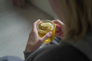 Hasta kadın evde bir bardaktan çay içiyor.