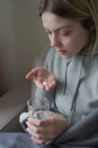 Malato giovani donne prendendo pillole mentre seduto sul divano a casa — Foto Stock