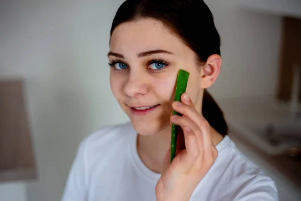 Jovem mulher segura folha de aloe vera na cozinha — Fotografia de Stock