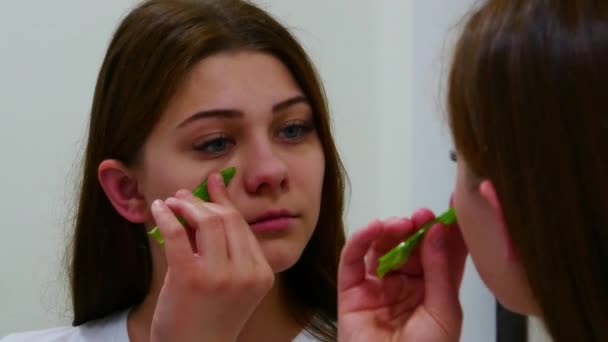 Flicka tittar i spegeln och använder aloe vera löv — Stockvideo