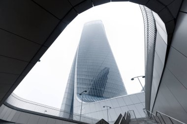 Mavi pencereli büyük bir ofis binasına çıkan büyük gri bir merdiven. 01.2020 Milano.