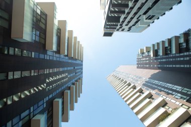 Mavi gökyüzüne karşı balkonlu bir daire oluşturan üç çok katlı fütüristik binanın görüntüsü. 01.20 Milano.