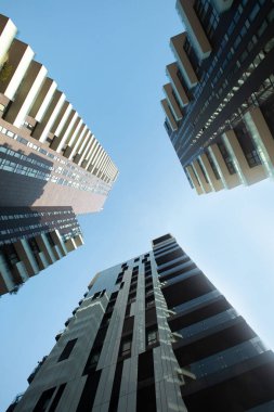 Mavi gökyüzüne karşı balkonlu bir daire oluşturan üç gökdelenli fütüristik binanın görüntüsü. Fotoğrafın dikey düzenlenmesi. 01.20 Milano
