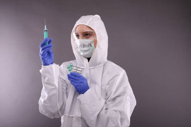 Koruyucu giysili ve maskeli kadın hapların üzerinde 