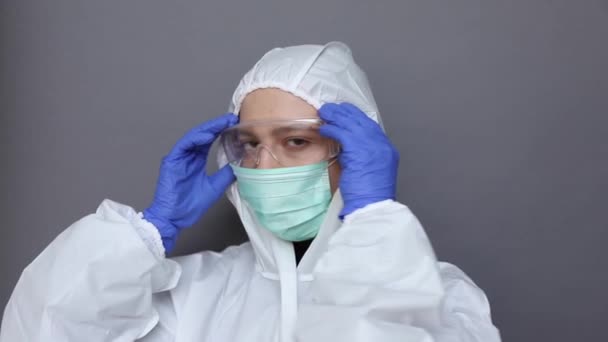 Close up de uma mulher em traje protetor colocando óculos e máscara — Vídeo de Stock