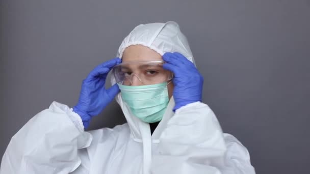 Primer plano de una mujer en traje protector poniéndose gafas y máscara — Vídeos de Stock