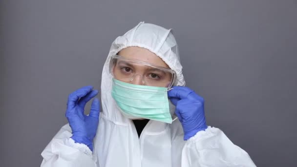 Läkare i skyddsdräkt tar på sig en mask — Stockvideo
