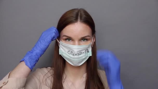 Egy nő levesz egy orvosi maszkot egy kovid-19 szöveggel. — Stock videók