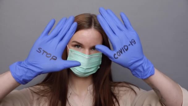 Frau mit Schutzmaske und Handschuhen zeigt "Stop COVID-19 — Stockvideo