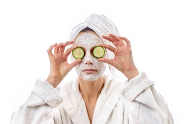 Beyaz kremalı yüzü ve sulu taze salatalıkları olan güzel genç bir kadın. Beyaz izole arkaplan.