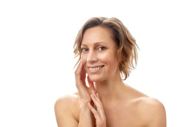 Kısa saçlı güzel bir kadın tenine dokunuyor ve gülümsüyor. Temiz cilt. Tepeden tırnağa çıplak poz. izole edilmiş beyaz arkaplan.