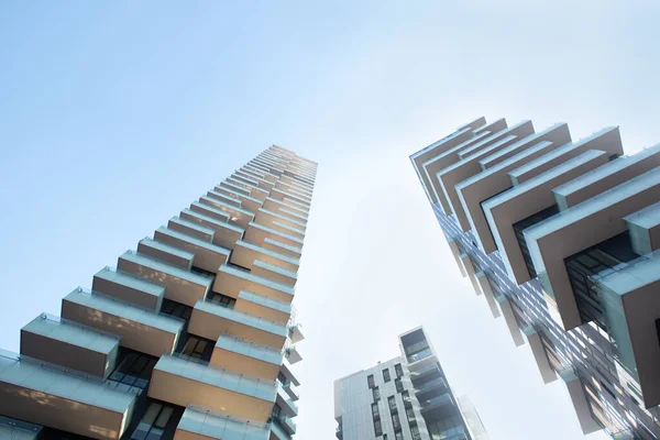 Buildings of different geometric shapes with large balconies harmoniously harmonize with each other in white against a blue sky. 01.2020 Milan — Stock Photo, Image