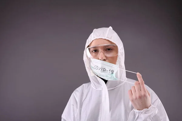 Frau im Schutzanzug setzt Maske "Coronavirus" auf" — Stockfoto