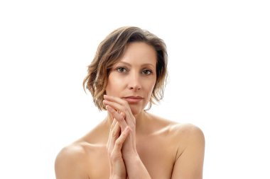 Güzel genç bir kadın, elleri birbirine kenetlenmiş kameraya bakıyor. Temiz cilt. Tepeden tırnağa çıplak poz. izole edilmiş beyaz arkaplan.