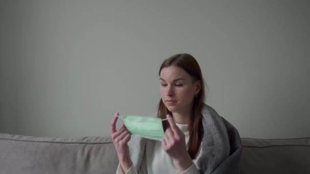 Uma linda jovem mostra como usar uma máscara médica em privado. Orvi, coronovírus, gripe, doença respiratória aguda — Vídeo de Stock