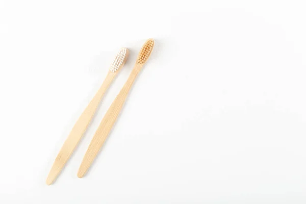 Dos cepillos de dientes hechos de materiales ecológicos, madera natural, se encuentran cerca. Sobre fondo blanco . — Foto de Stock