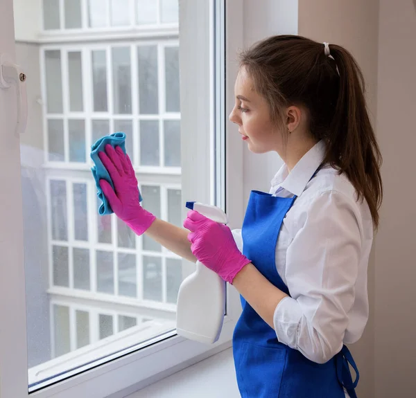 Flickan applicerar rengöringsmedel med en sprutpistol fönster. — Stockfoto