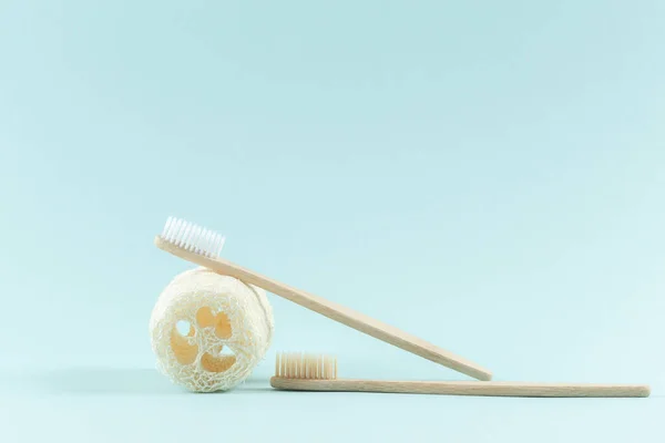 Dos cepillos de dientes hechos de madera. Producto de esponja natural para el cuerpo. Residuos cero. Sobre un fondo azul de moda . — Foto de Stock