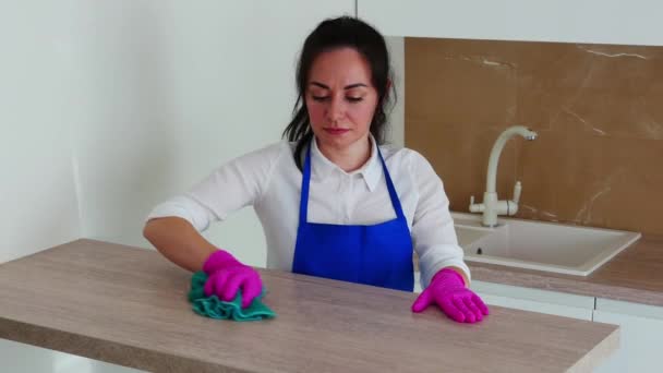 La morena se dedica a la limpieza. Limpia una mesa de madera clara . — Vídeos de Stock